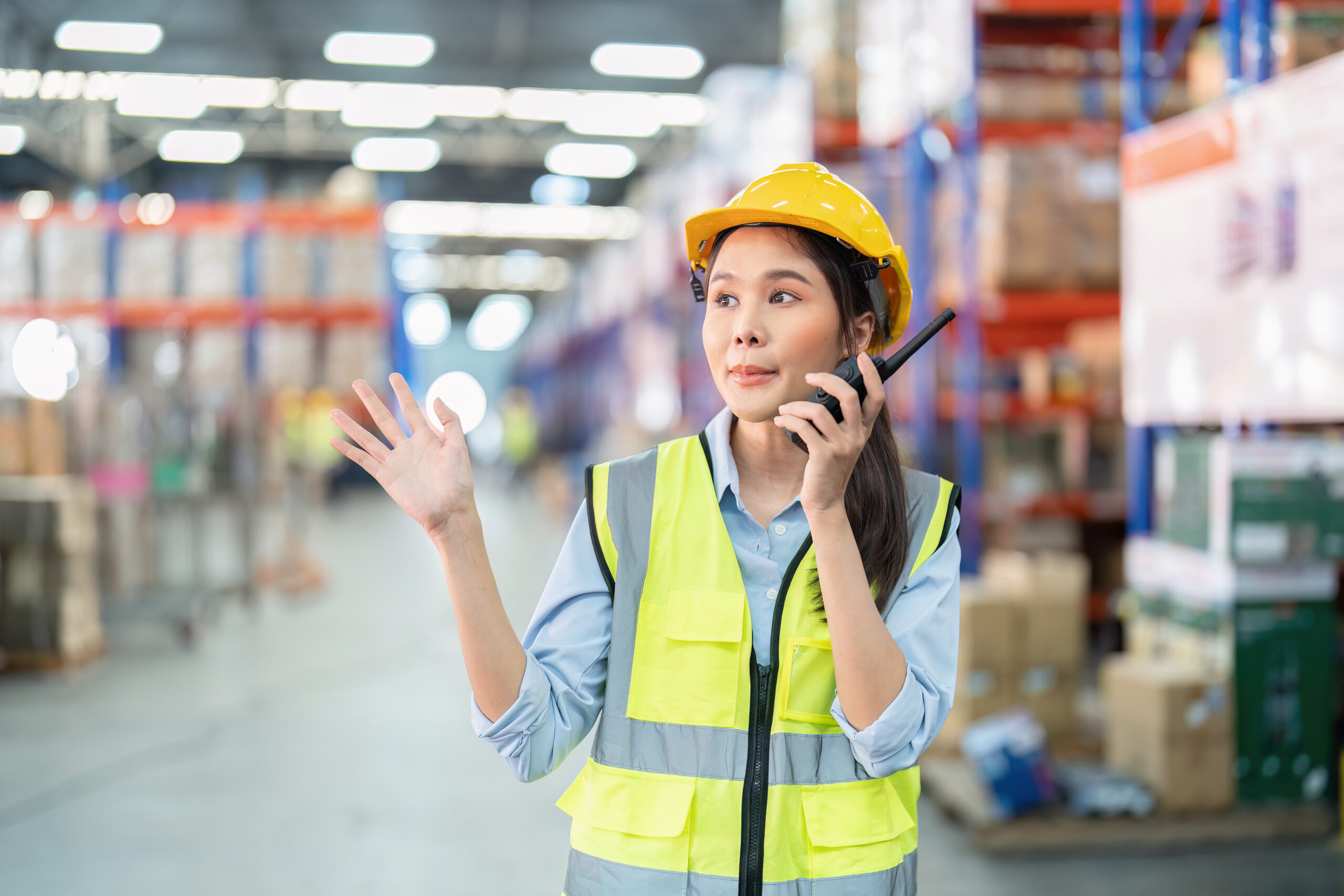Staff in large storage warehouse use radio walkie talkie explain material storage location to team